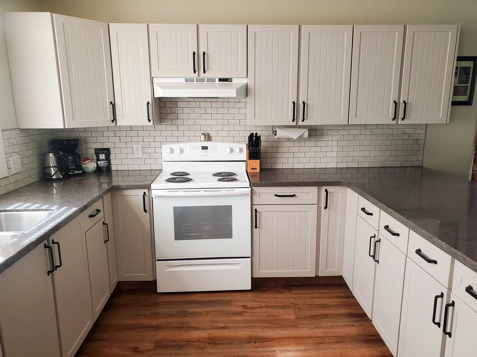 Custom range hood and granite counters in a finished Kelowna-area kitchen